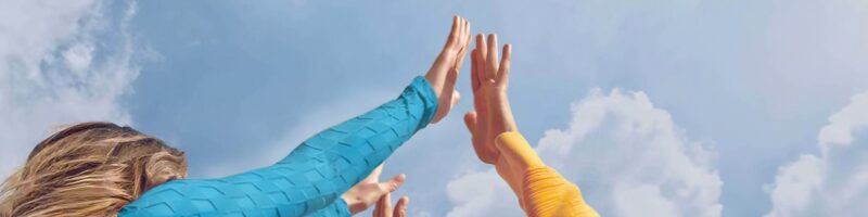 People raising hands together toward the sky, symbolizing collaboration, partnership, and shared progress in clinical research.