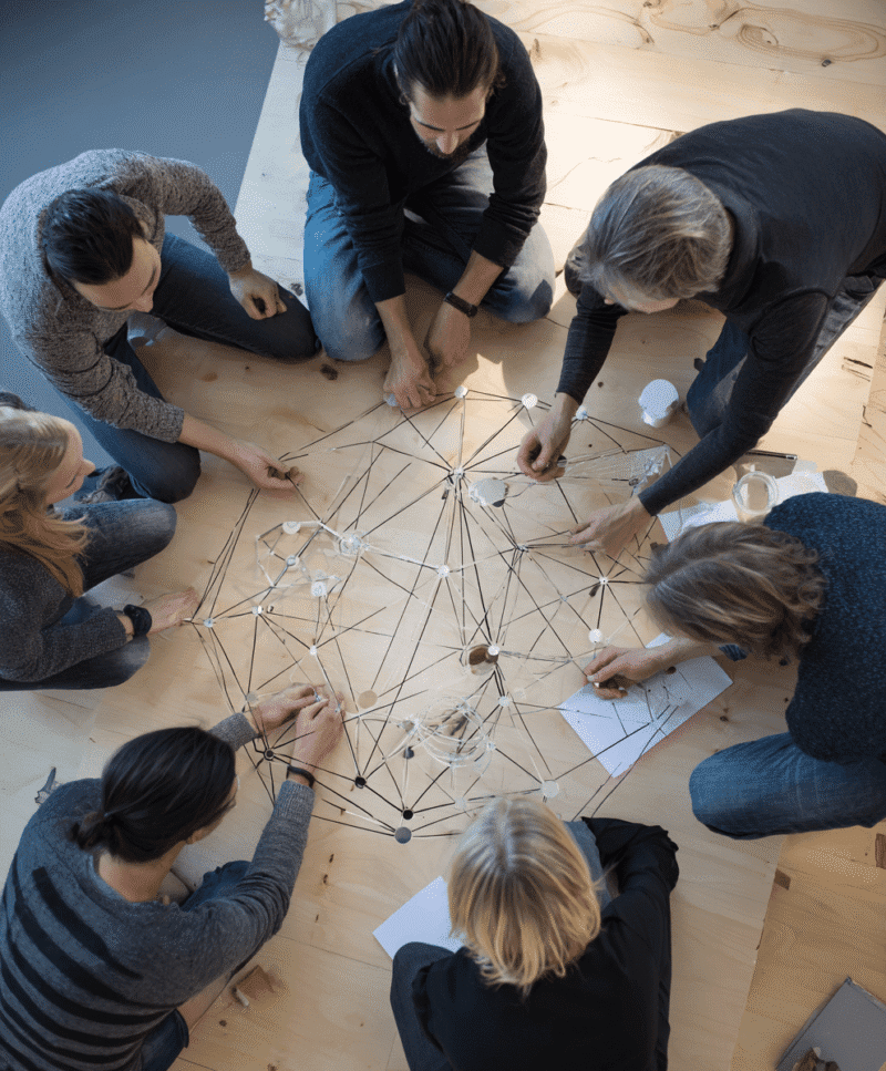 Équipe collaborant autour d’un modèle de réseau connecté, illustrant la coordination full service provider et le soutien transversal aux essais cliniques.